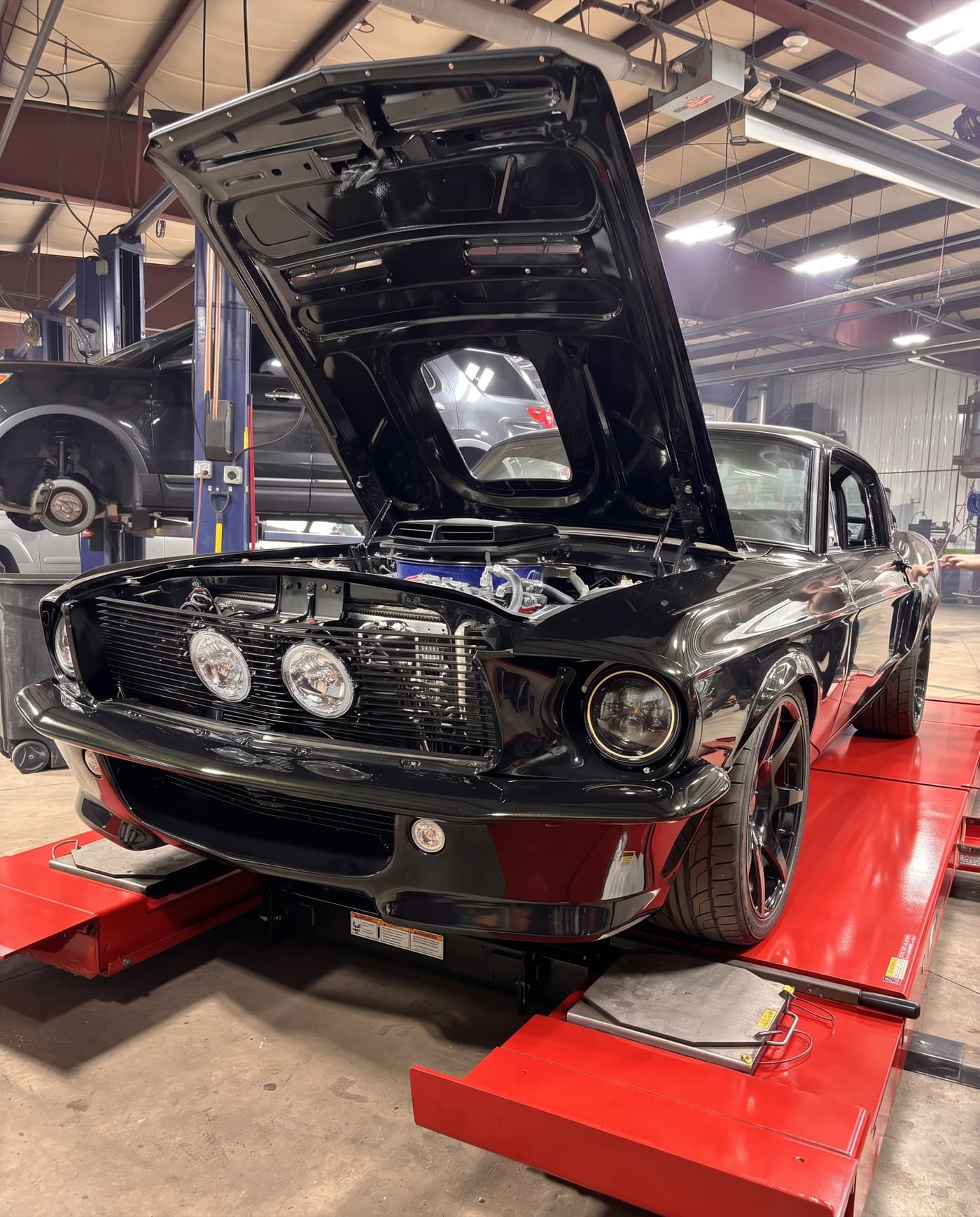 A restored black Ford Mustang fastback up on the alignment rack at Complete Auto Tech Center in Fall River